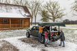 Group of people loading a truck with a canoe on top and cargo in the bottom in a snowy landscape near a wooden cabin. Featuring BAKFlip MX4 TS. 
