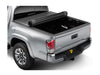 Image of a hard roll up tonneau cover. Cover is halfway rolled up to expose a portion of the bed. Silver Toyota Tacoma. 
