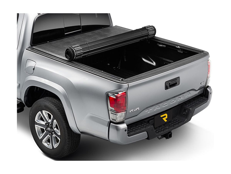 Image of a hard roll up tonneau cover. Cover is halfway rolled up to expose a portion of the bed. Silver Toyota Tacoma. 