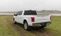 A white Ford truck with an Access Vanish Roll-Up Tonneau Cover, parked in a grassy field under a clear sky.