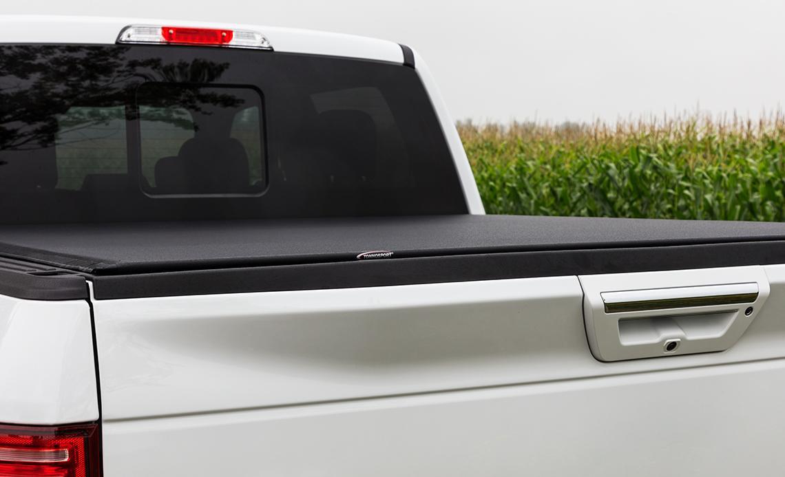 Rear of a white truck with a black Access LiteRider Roll-Up Tonneau Cover installed.