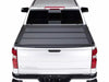 Back view of a white truck featuring a BAKFlip MX4 black tonneau cover on its bed.
