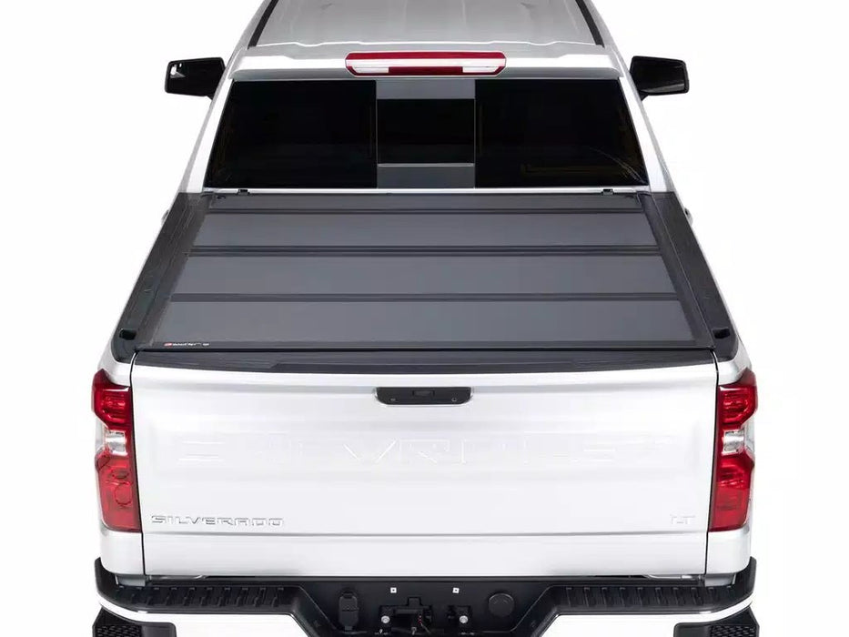 Back view of a white truck featuring a BAKFlip MX4 black tonneau cover on its bed.