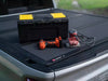 Truck bed with various tools and a BAKFlip MX4 Tonneau Cover, showcasing a practical work setup.
