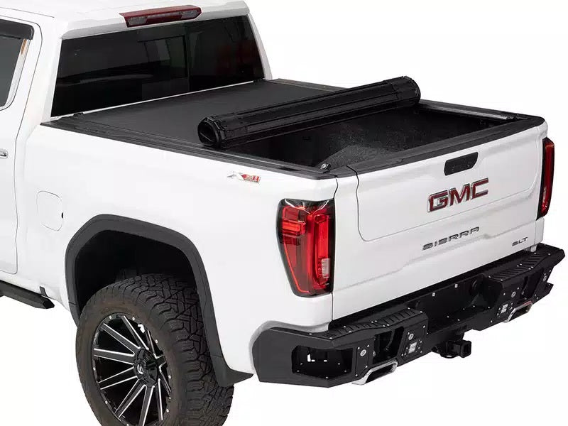 Rear of a white truck with a black bed, showcasing a Bak Tonneau Cover.